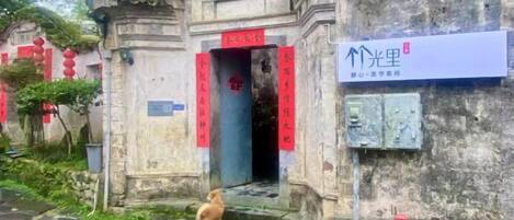 Un bâtiment traditionnel avec une entrée en pierre, une enseigne et un petit chien près de l’entrée.