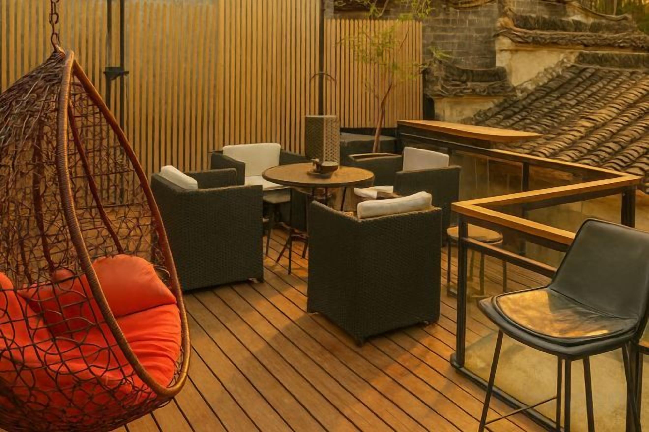 A wooden deck with outdoor furniture, including a hanging chair, sofas, and a table.
