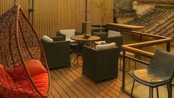 A wooden deck with outdoor furniture, including a hanging chair, sofas, and a table.