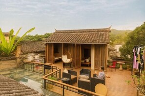 Un bâtiment de style traditionnel, doté d’une façade en bois et d’un patio vitré avec un espace extérieur aménagé pour s’asseoir.