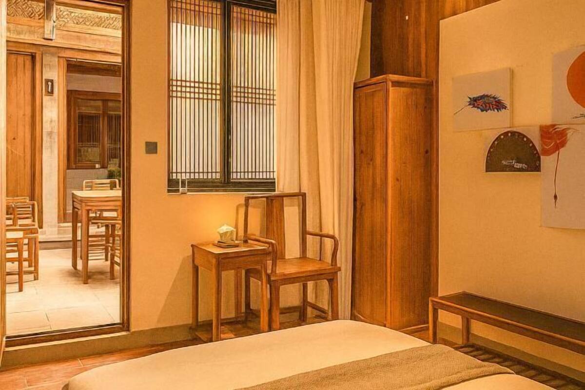 Une pièce de style japonais traditionnel, avec un sol recouvert de tatamis, un lit bas en bois, une petite table avec une chaise et une porte coulissante donnant sur un coin repas.
