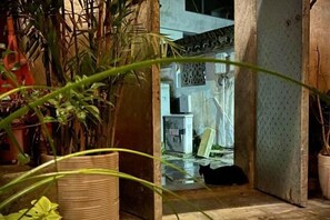 A narrow hallway with a potted plant, a door, and a small table with a chair. - Xidi Zhuguangli · Mindful Aesthetic Homestay (Yi County)