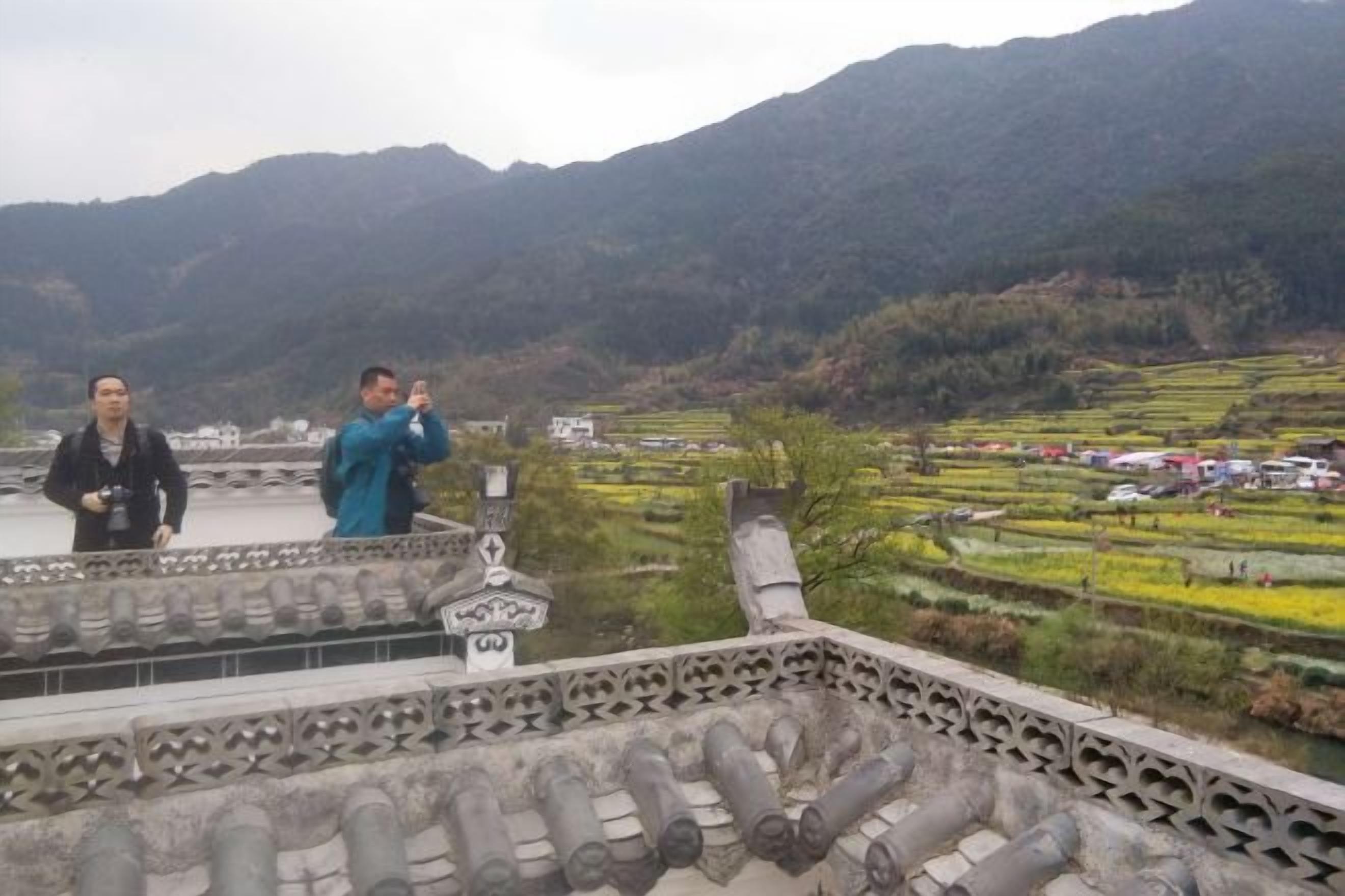 A traditional building with a tiled roof and a view of terraced fields.