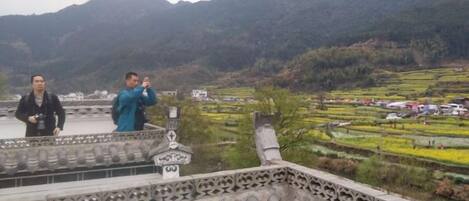 A traditional building with a tiled roof and a view of terraced fields.