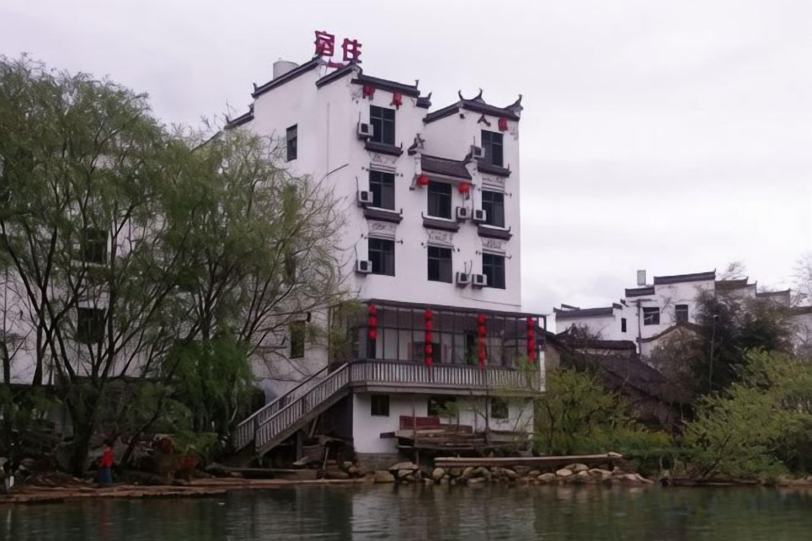 A traditional building with a staircase leading to a balcony, situated by a body of water.