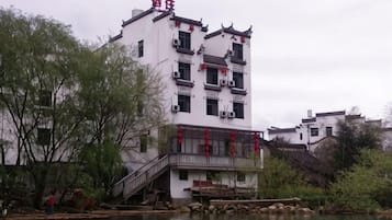 A traditional building with a staircase leading to a balcony, situated by a body of water.