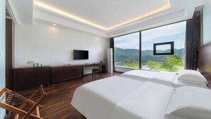 Una habitación de hotel moderna con una cama grande, un escritorio, una silla y un televisor.
