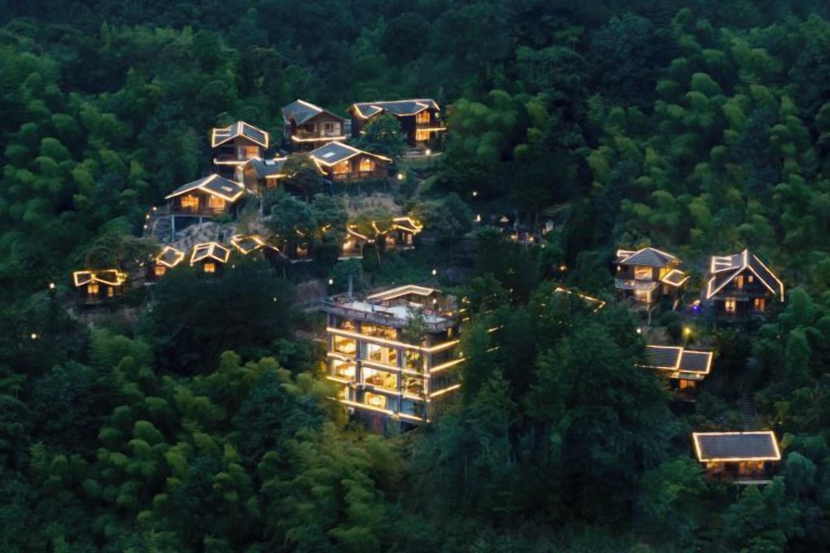 A cluster of multi-story buildings with multiple balconies, surrounded by dense forest.