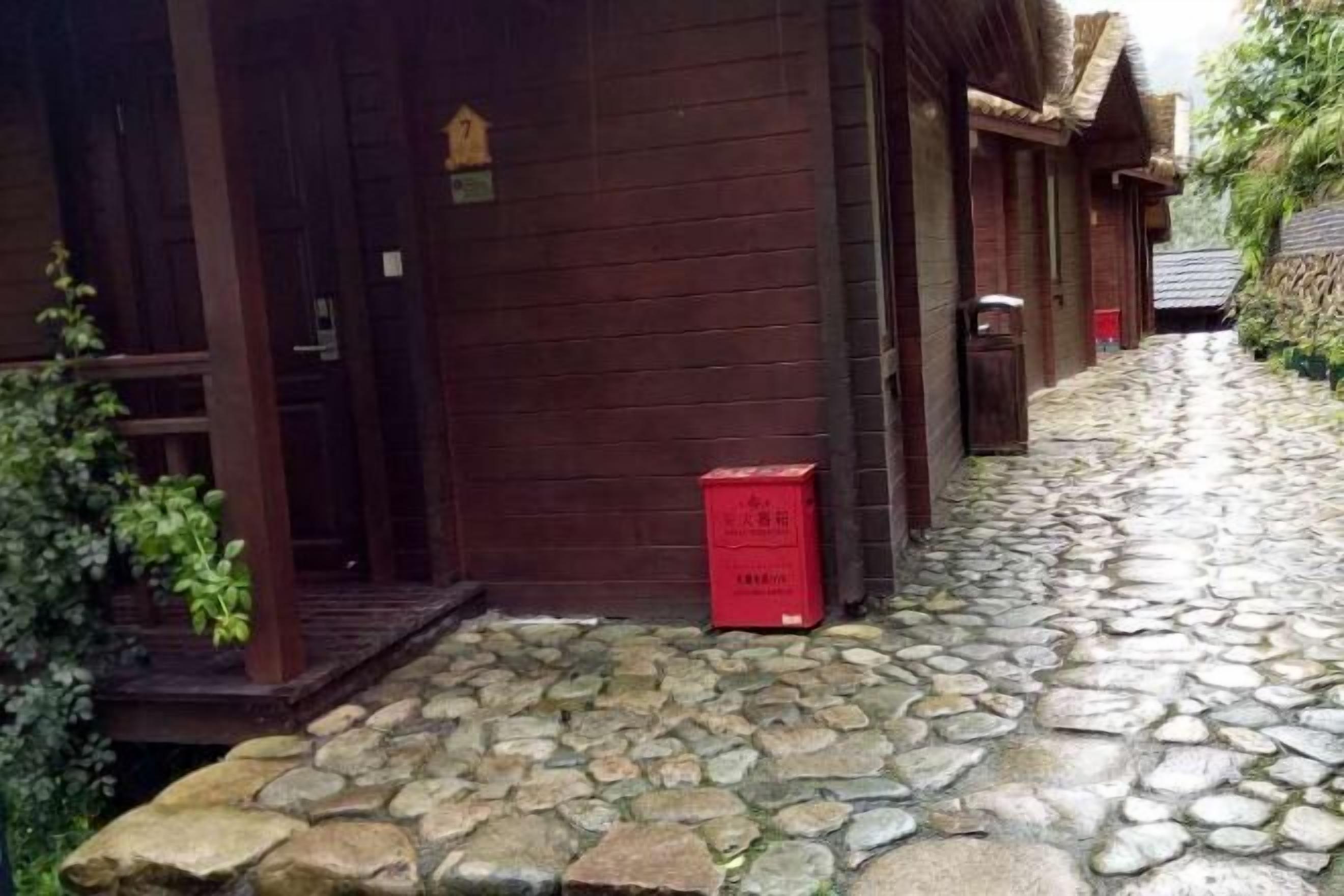 Ein gepflasterter Weg führt zu einem Holzhaus mit der Hausnummer 7.