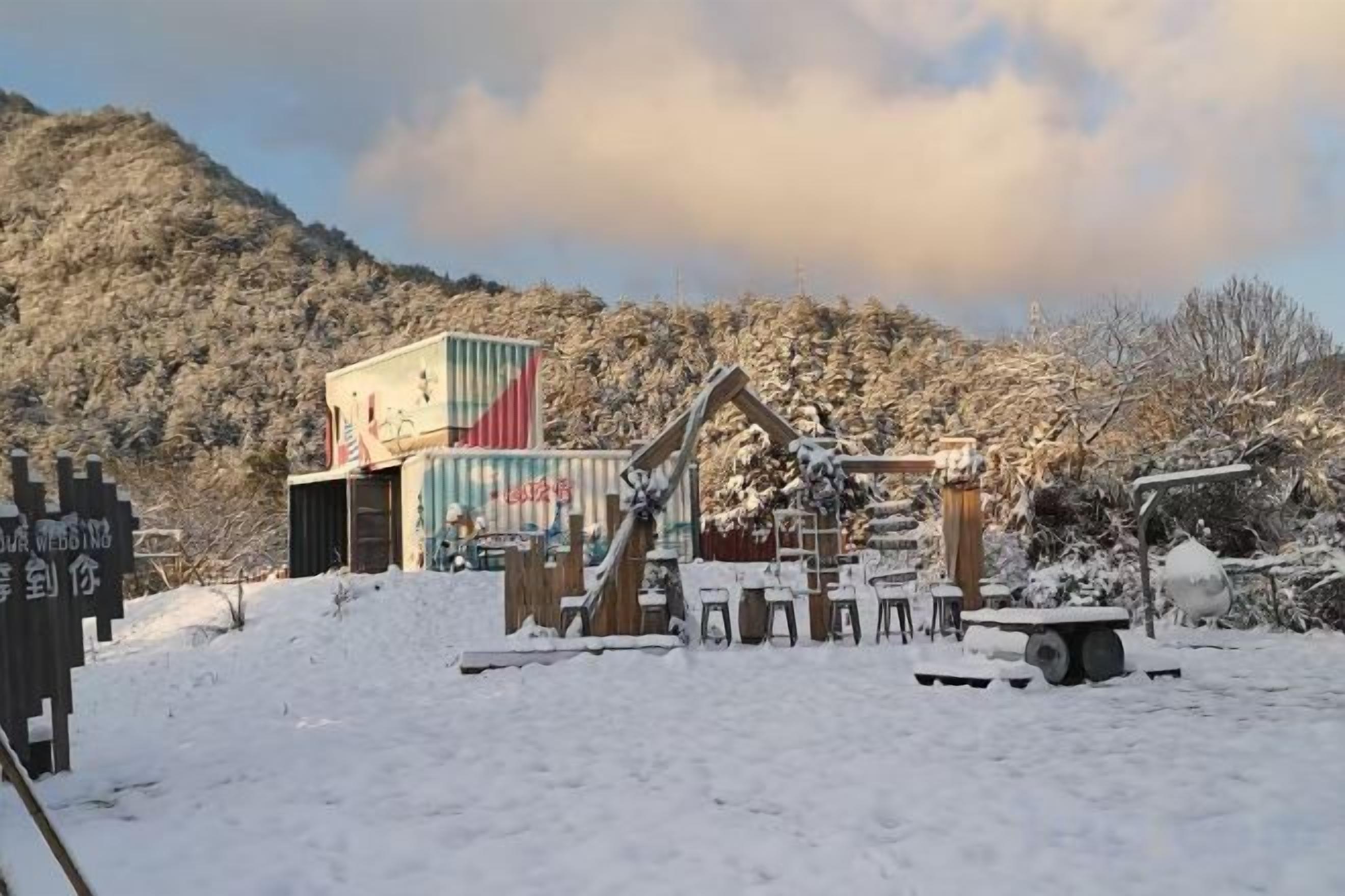 A snow-covered outdoor area with a wooden structure and a colorful container.