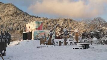 A snow-covered outdoor area with a wooden structure and a colorful container.