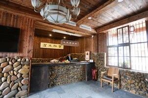 Un área de recepción con pared de piedra, paneles de madera, un mostrador de recepción y un ventanal con barrotes.