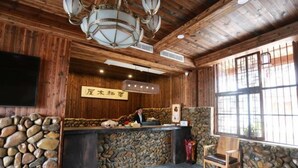 Una zona de recepción con pared de piedra, techo de madera y mostrador de recepción también de madera.