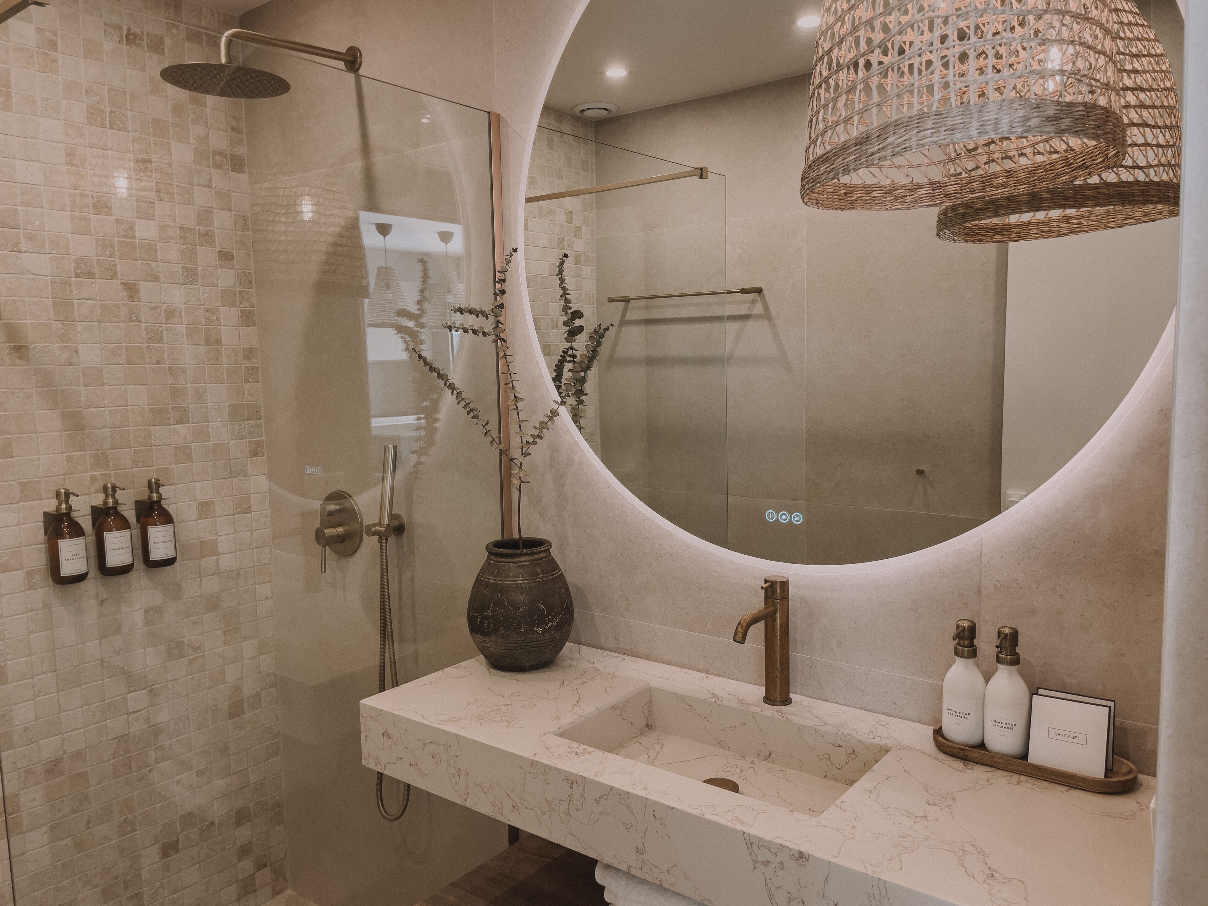Un bagno moderno con doccia vetrata, lavabo in marmo e un ampio specchio.