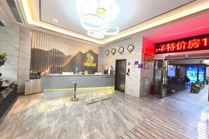 A hotel reception area with a modern design, a reception desk, and a digital display. - Kaiyue Business Hostel (Nanping)
