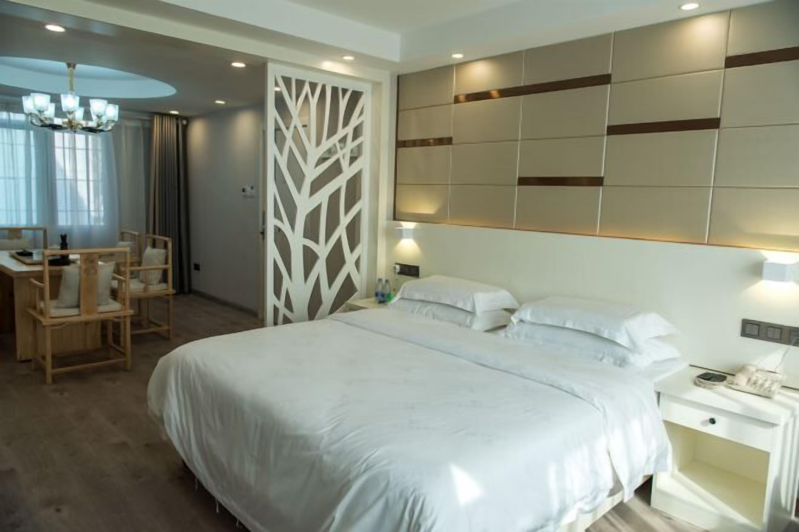 Un dormitorio con una cama grande, mesitas de noche, un escritorio con sillas y un panel decorativo en la pared.