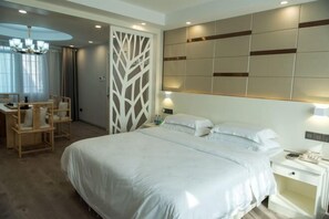 Un dormitorio con una cama grande, mesitas de noche, un escritorio con sillas y un panel decorativo en la pared.