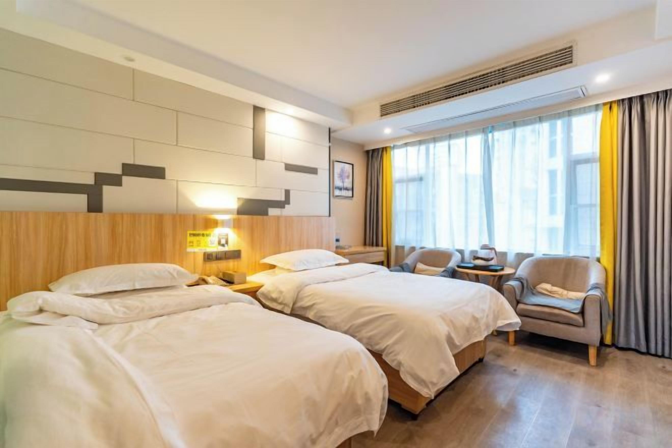 A hotel room with two beds, a sofa, a small table, and a window with curtains.