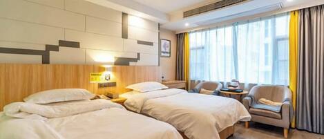 A hotel room with two beds, a sofa, a small table, and a window with curtains.