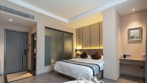 Een moderne hotelkamer met een groot bed, nachtkastjes, een bureau en uitzicht op de stad.