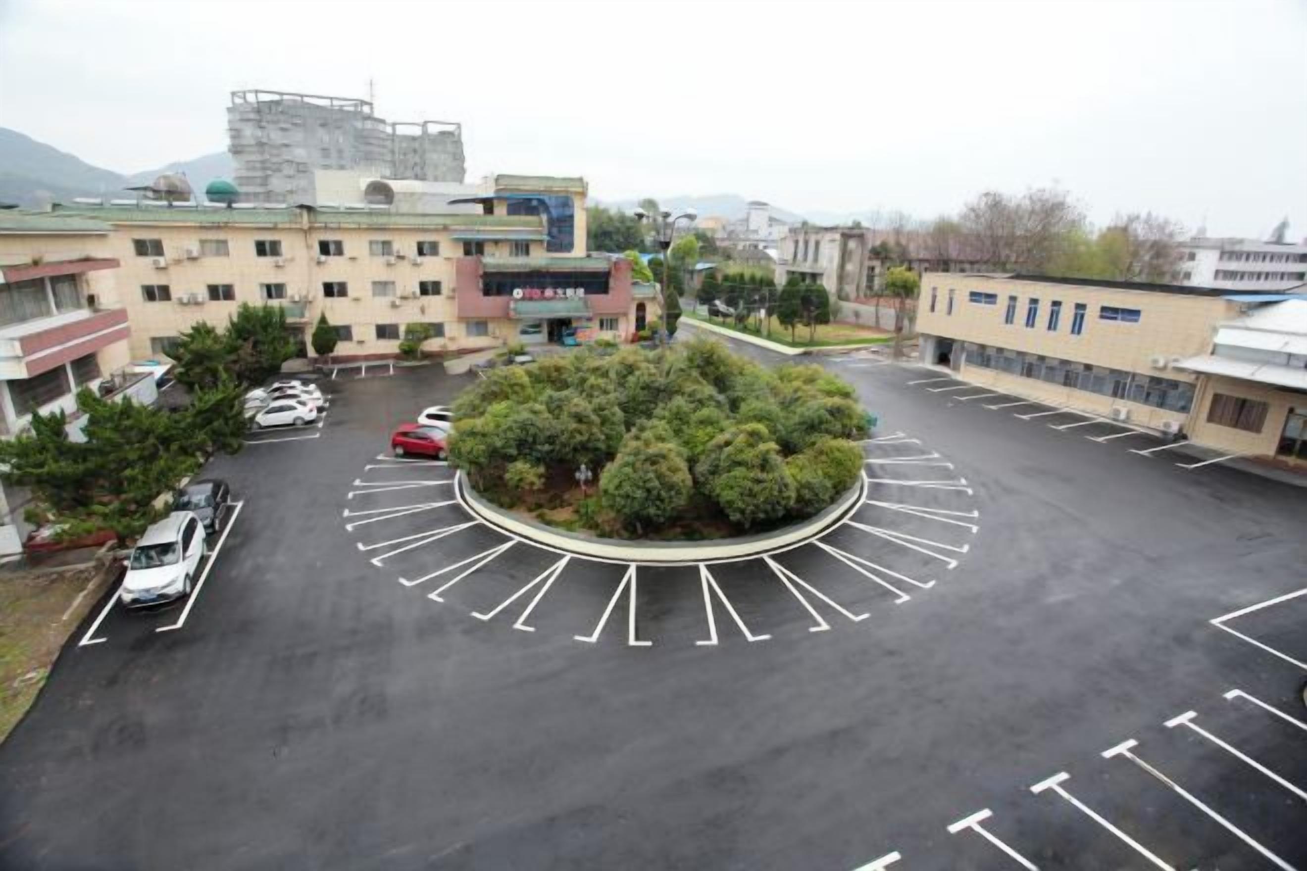 A parking lot with a central landscaped area, surrounded by buildings with multiple floors and various architectural styles.
