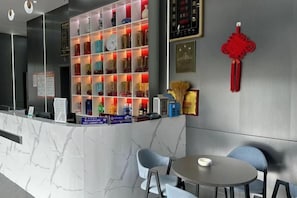 Un espace d’accueil avec un comptoir en marbre, des étagères remplies de divers objets et deux chaises.
