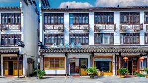 A traditional building with multiple balconies and a sign above the entrance. - Wuzhen Zhonglitunta Chinese Inn (Tongxiang)