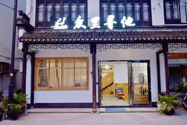 Traditional Chinese architecture with a tiled roof and decorative entrance, featuring a wooden door and potted plants.