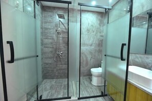 Cabina doccia in vetro con soffione a mano, water e specchio.