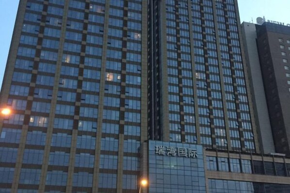 A high-rise building with a grid of windows and a sign that reads "瑞港国际". - Sunny International Apartment (Tianjin)