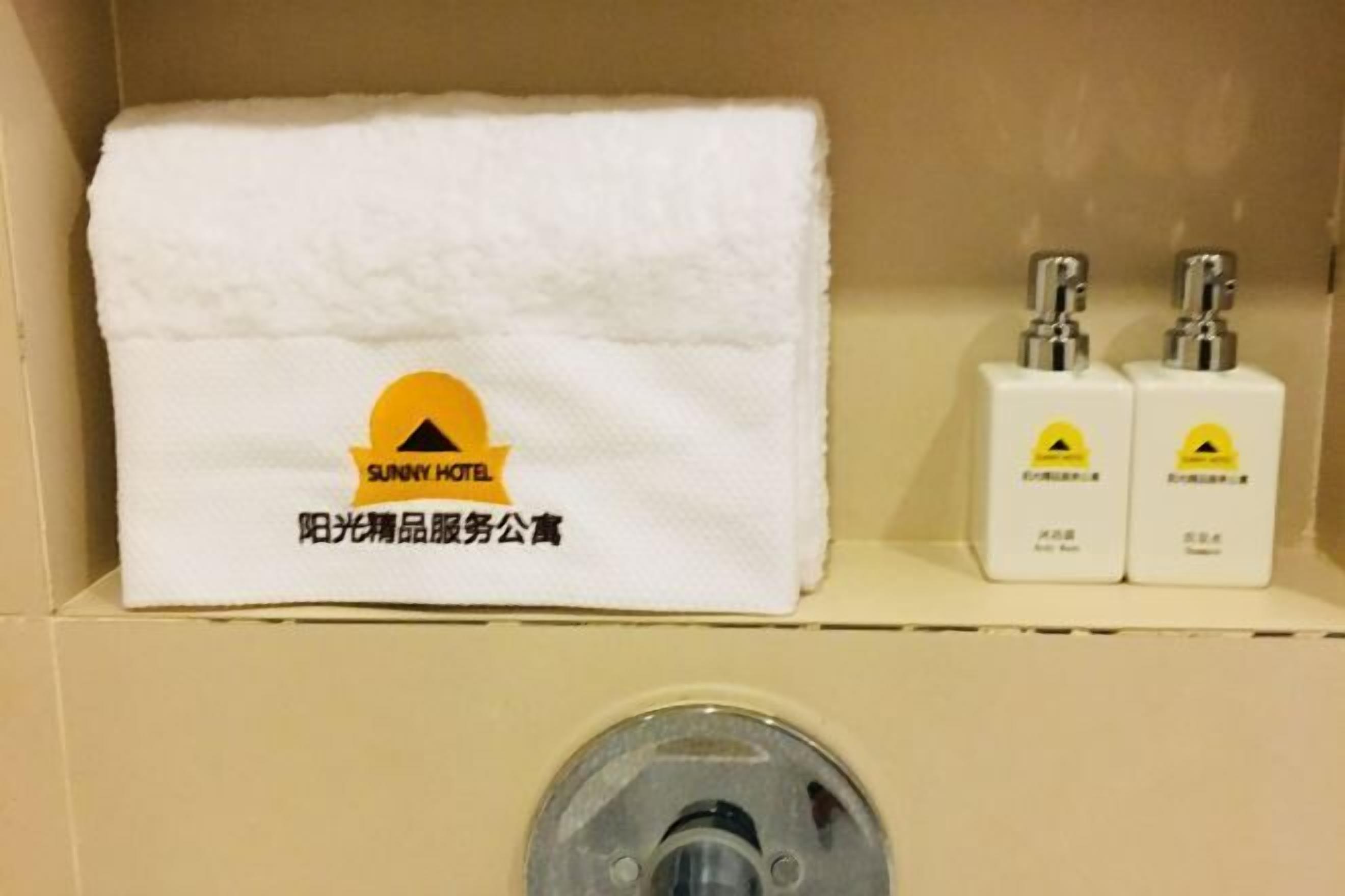 Un baño con una toalla blanca, dos artículos de tocador y un lavamanos.