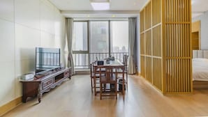 Une chambre d’hôtel avec un coin repas, une télévision et une grande fenêtre donnant sur un beau paysage.