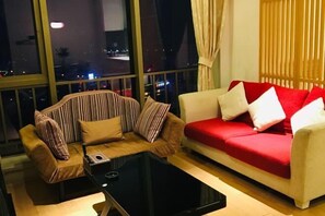 A living room with a striped sofa, a red sofa, and a black coffee table.