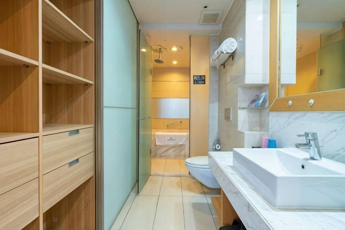 Une salle de bain moderne avec un lavabo blanc, un miroir et des étagères en bois.