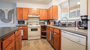 A kitchen with wooden cabinets, a microwave, stove, dishwasher, and a window with a view. - Waterfront Retreat, Relaxation, Fun in Hood Canal (Hoodsport)
