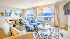 A living room with a sofa, armchair, coffee table, and a view of the outdoors. - Waterfront Retreat, Relaxation, Fun in Hood Canal (Hoodsport)