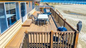 A wooden deck with a table and chairs, overlooking a beach and water. - Waterfront Retreat, Relaxation, Fun in Hood Canal (Hoodsport)