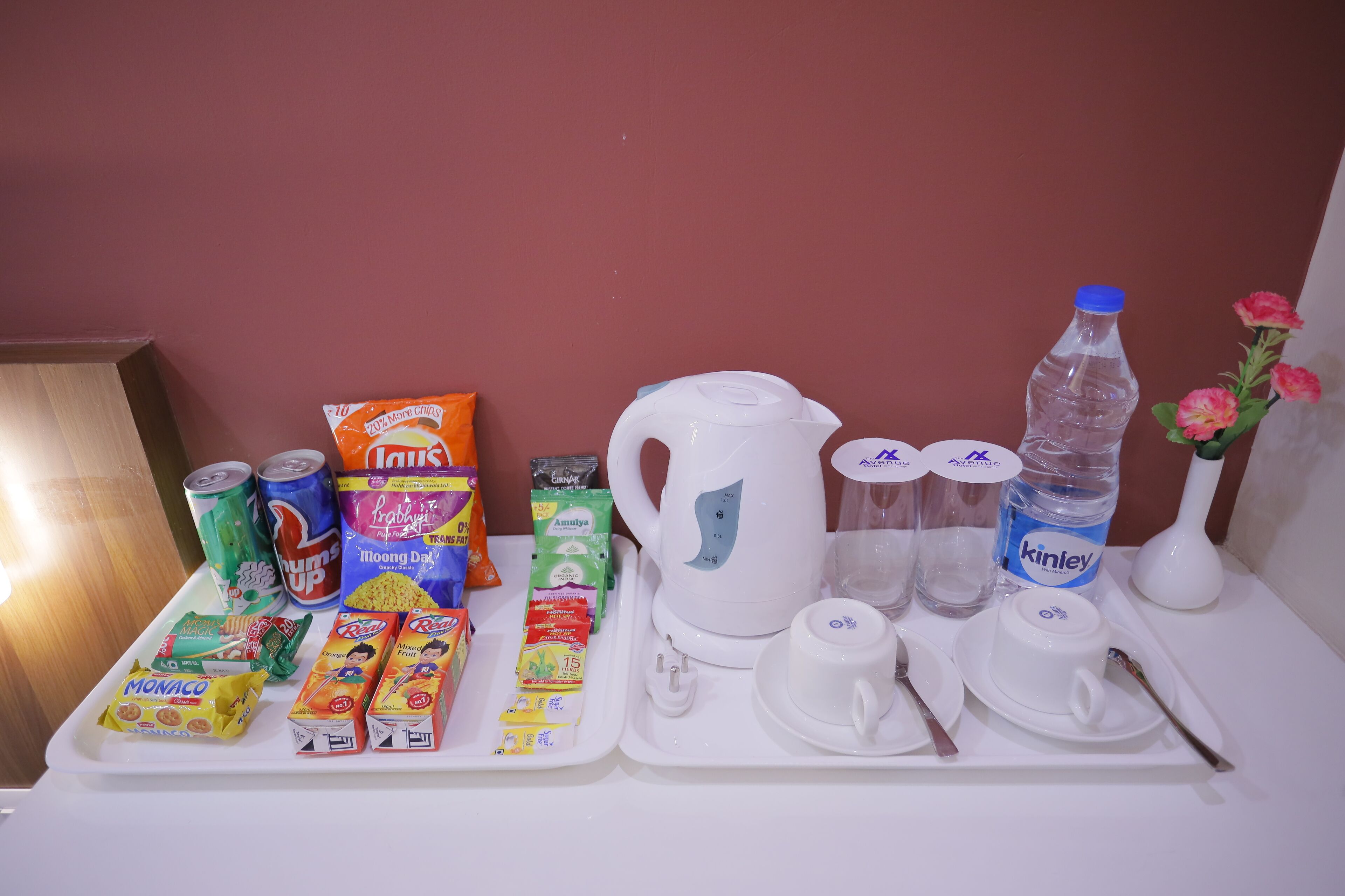 A breakfast tray with various food items, a kettle, cups, and a bottle of water.