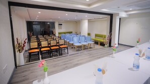 A conference room with rows of chairs, a table with water bottles, and a green sofa in the background.