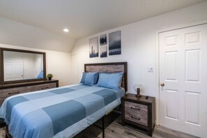 A bedroom with a bed, a nightstand, a dresser, a mirror, and a door. - Lakeside house with access to dunes, lakes, and the ocean! (Lakeside)