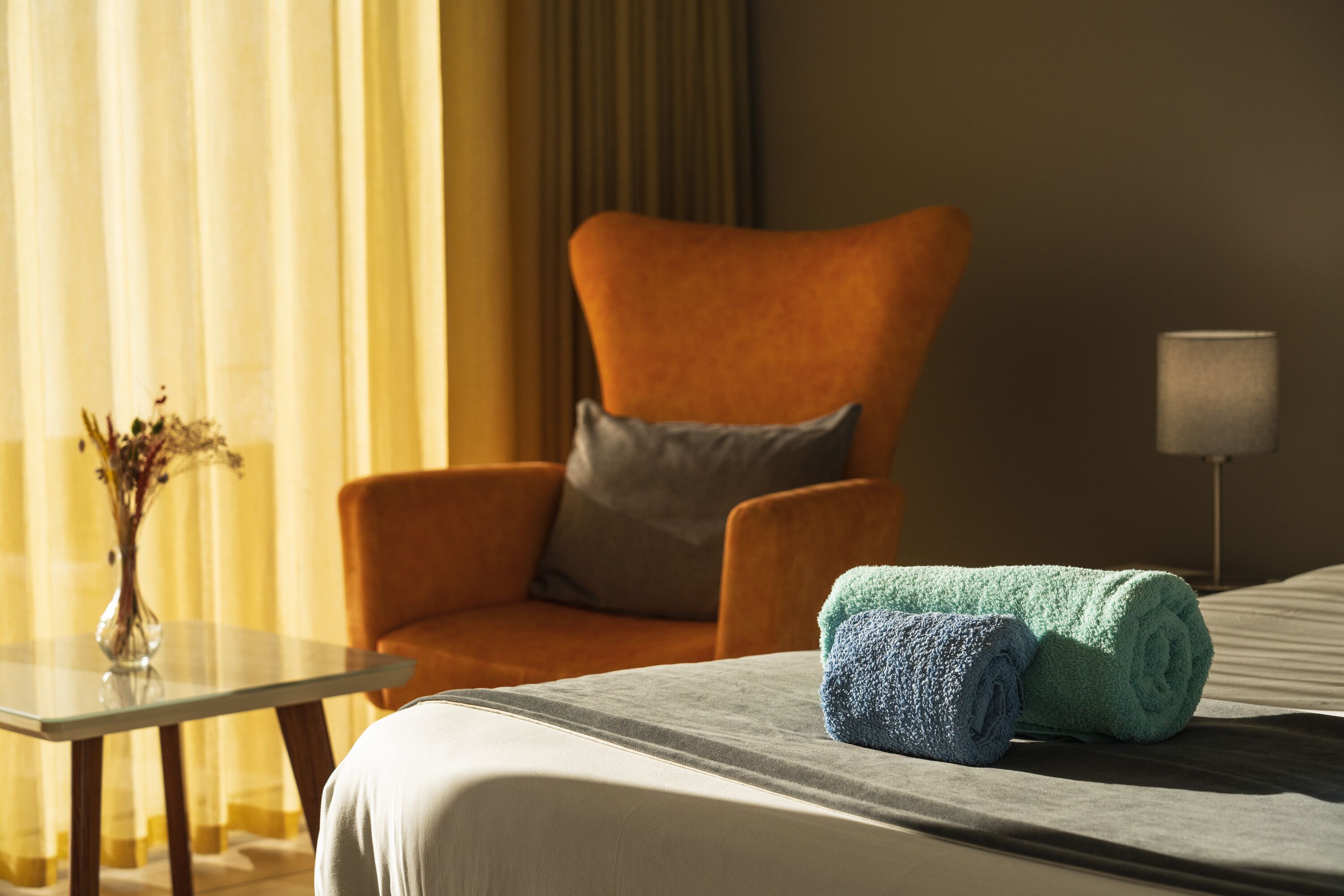 Una habitación de hotel con cama, una silla, una mesa y una lámpara.