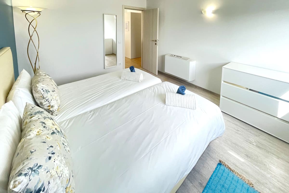 Ett hotellrum med två sängar, en stor spegel, ett nattduksbord, en byrå och en blå matta.