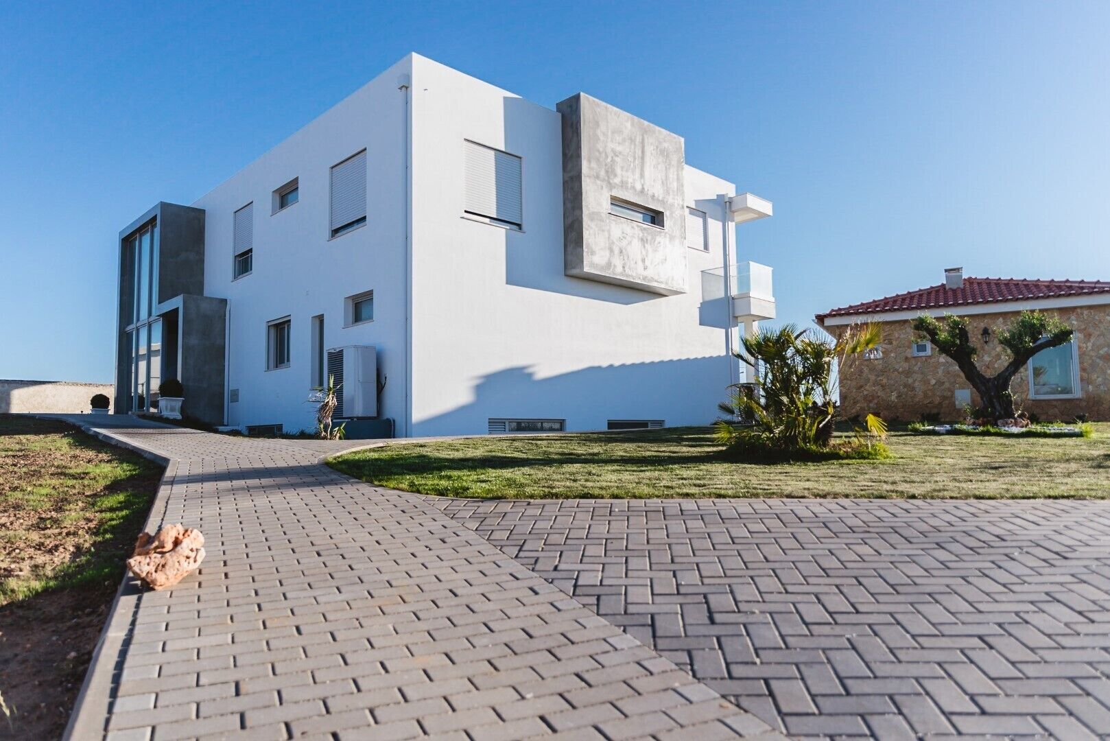Un bâtiment moderne à deux étages, doté d’un toit plat, de grandes fenêtres et d’une allée pavée.