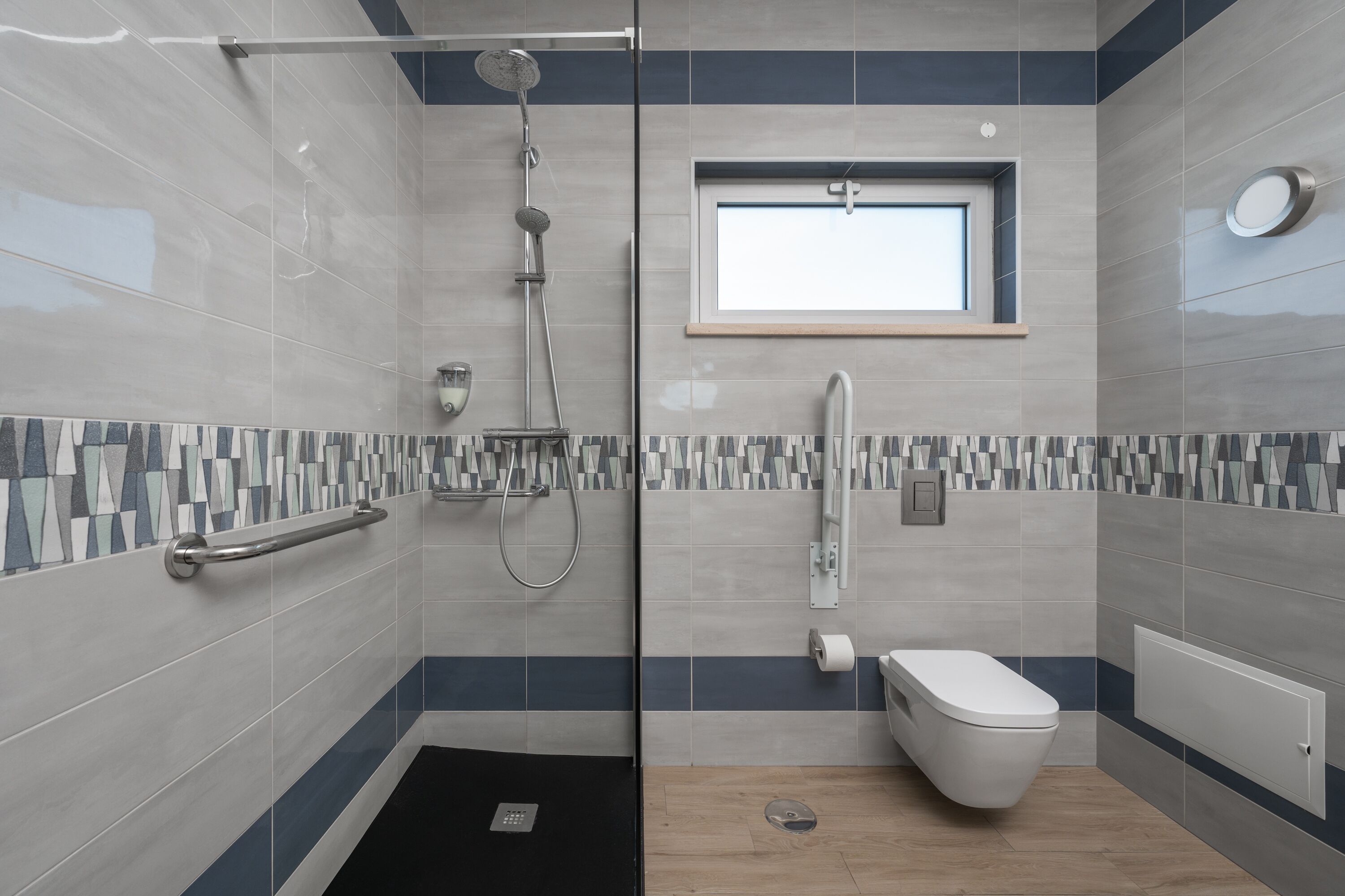Un baño moderno con ducha, inodoro y ventana.