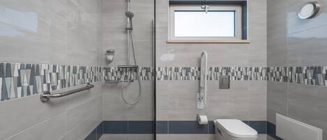 A modern bathroom with a shower, toilet, and a window.