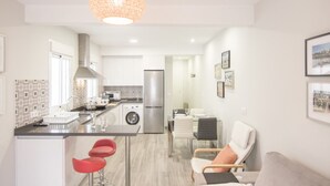 Una cocina moderna con una isla central, electrodomésticos de acero inoxidable y una lámpara colgante.