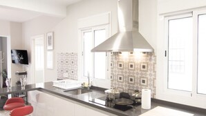Una cocina moderna con extractor de acero inoxidable, un lavamanos doble y una tabla de cortar de madera sobre la encimera.
