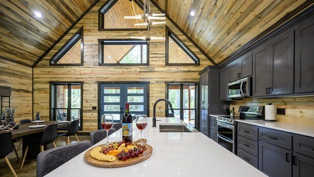 Une cuisine moderne dotée d’un grand îlot central, de meubles de couleur sombre et d’un plafond en bois.