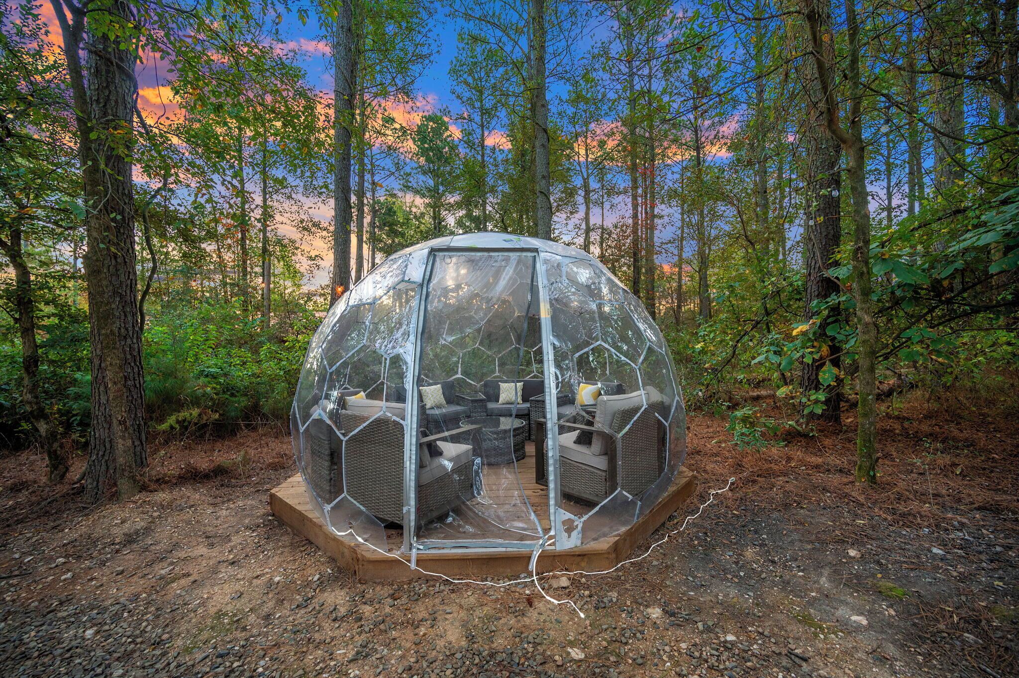 At twilight, the geodome transforms into a glowing retreat nestled among the trees.