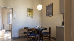 Zona de dinar amb una taula rodona, quatre cadires i dues làmpades fixades a la paret.